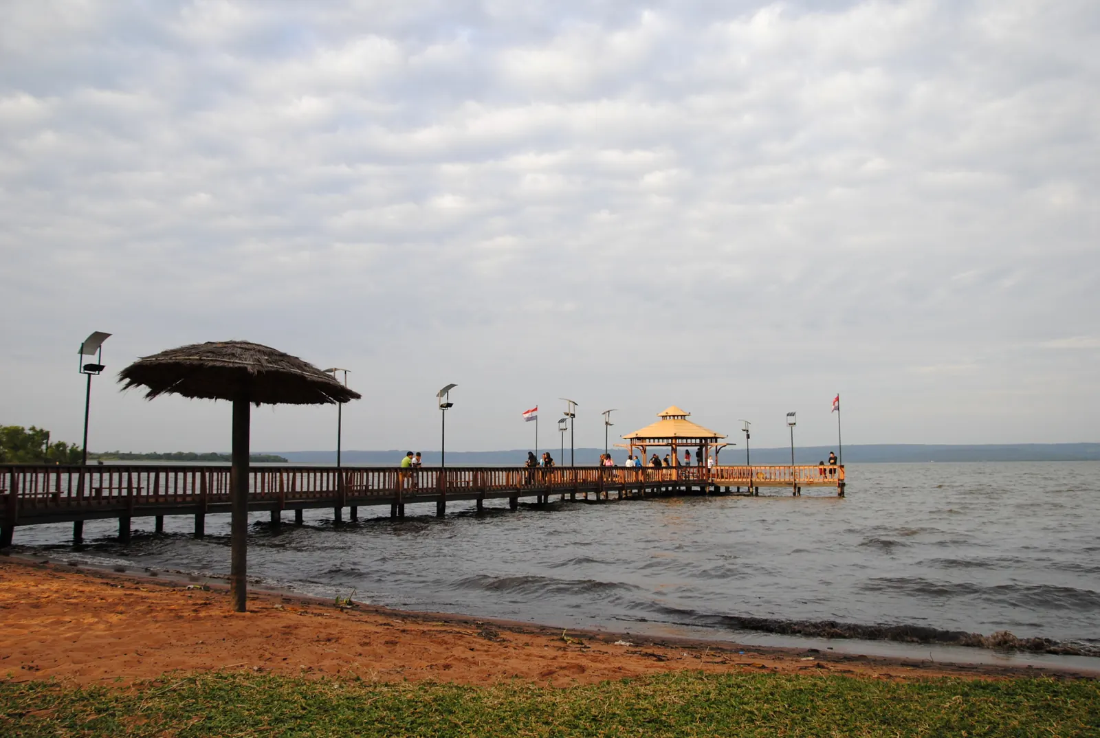 Wooden pier on the Lago Ypacaraí shore at the Areguá town beach, under a cloudy sky