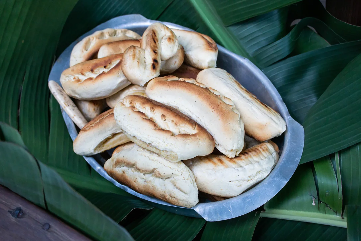 Chipas paraguaias recém-assadas em uma bandeja de metal sobre folhas verdes