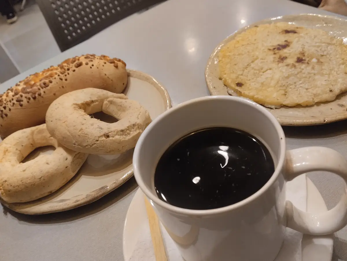 Chipa, uma xícara de cocido quemado e mbejú sobre uma mesa