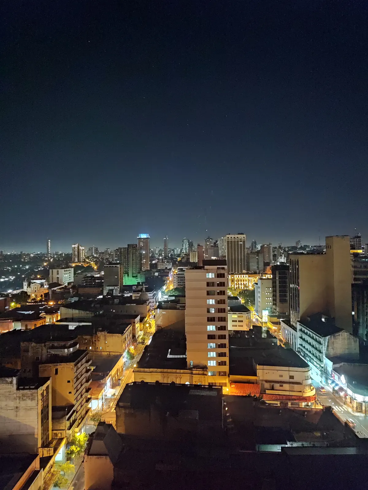 El centro de Asunción de noche visto desde una azotea, con calles iluminadas y torres bajo un cielo oscuro.
