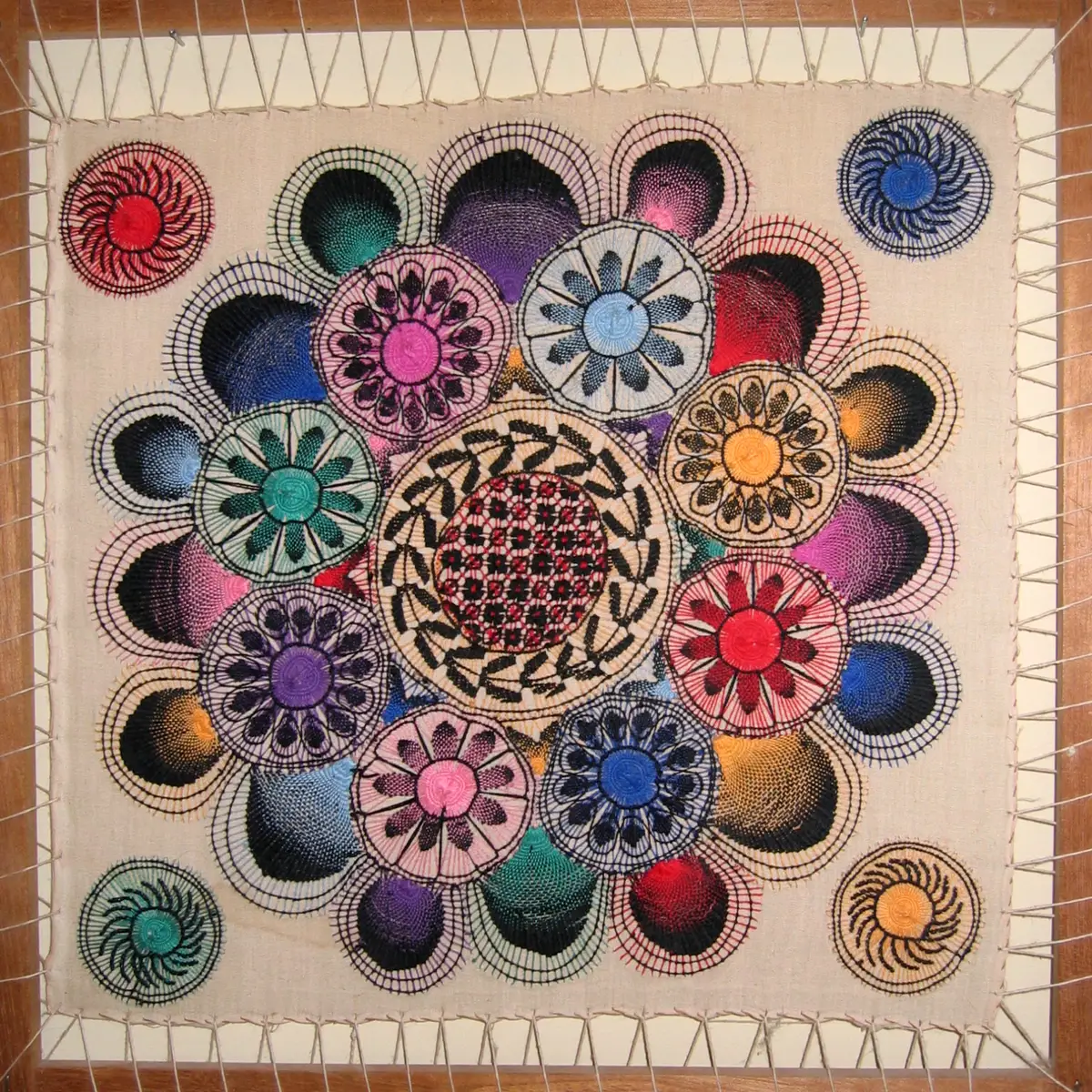 Ñandutí de colores con motivos circulares y florales tensado sobre un marco de madera