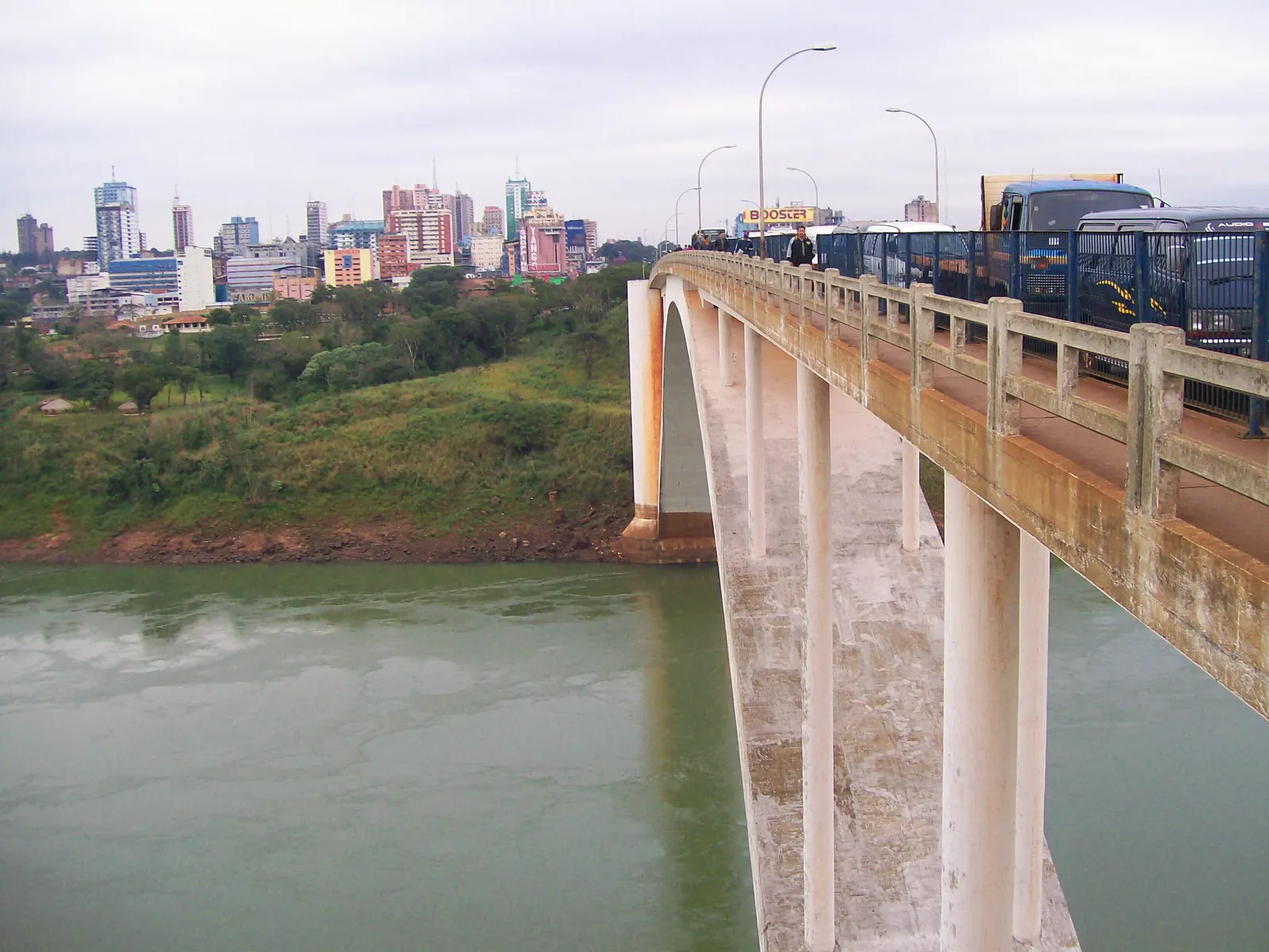 The Friendship Bridge carrying traffic over the green Paraná river, with the Ciudad del Este skyline behind
