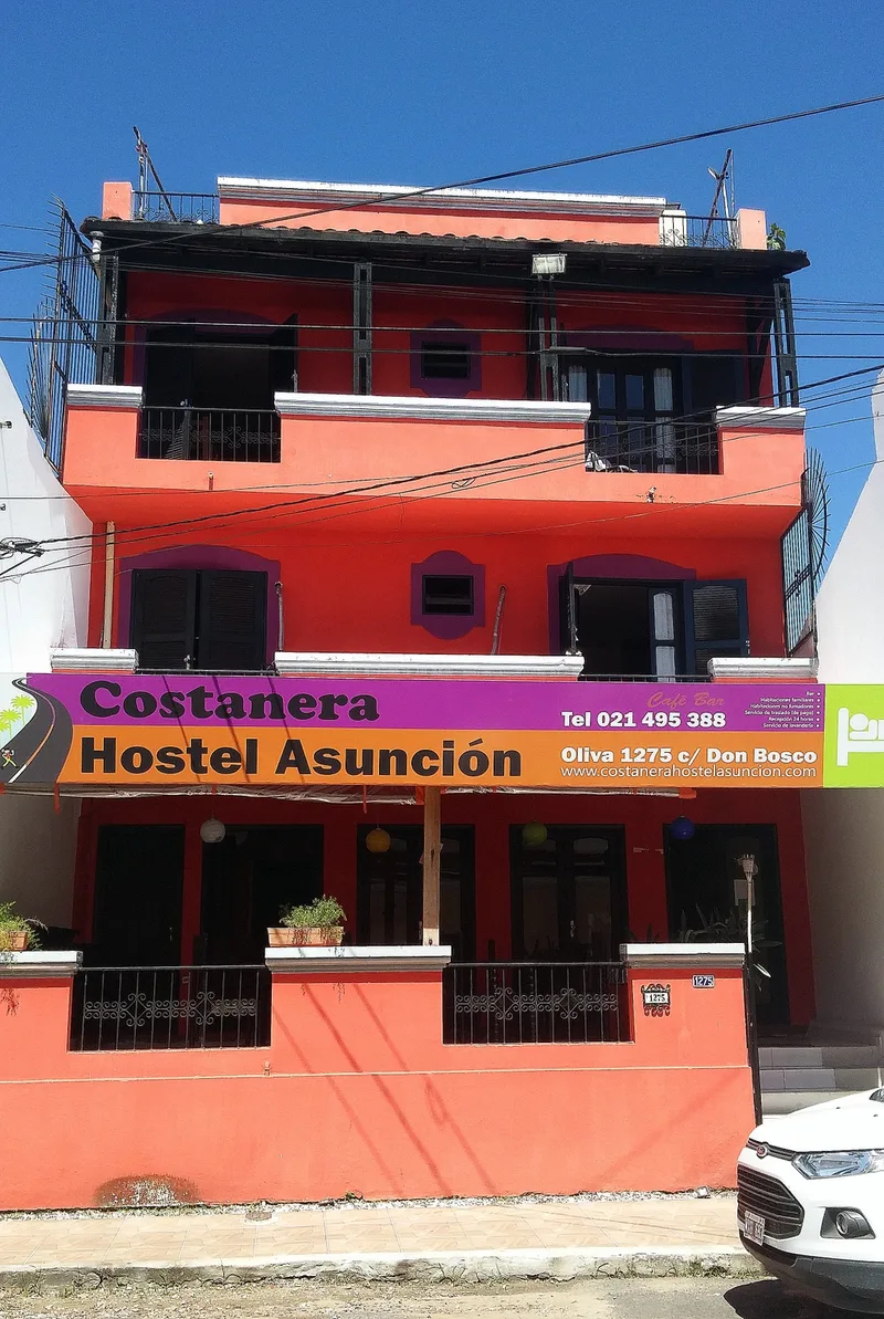 Fachada color coral del Costanera Hostel sobre la calle Oliva, fotografiada en 2017