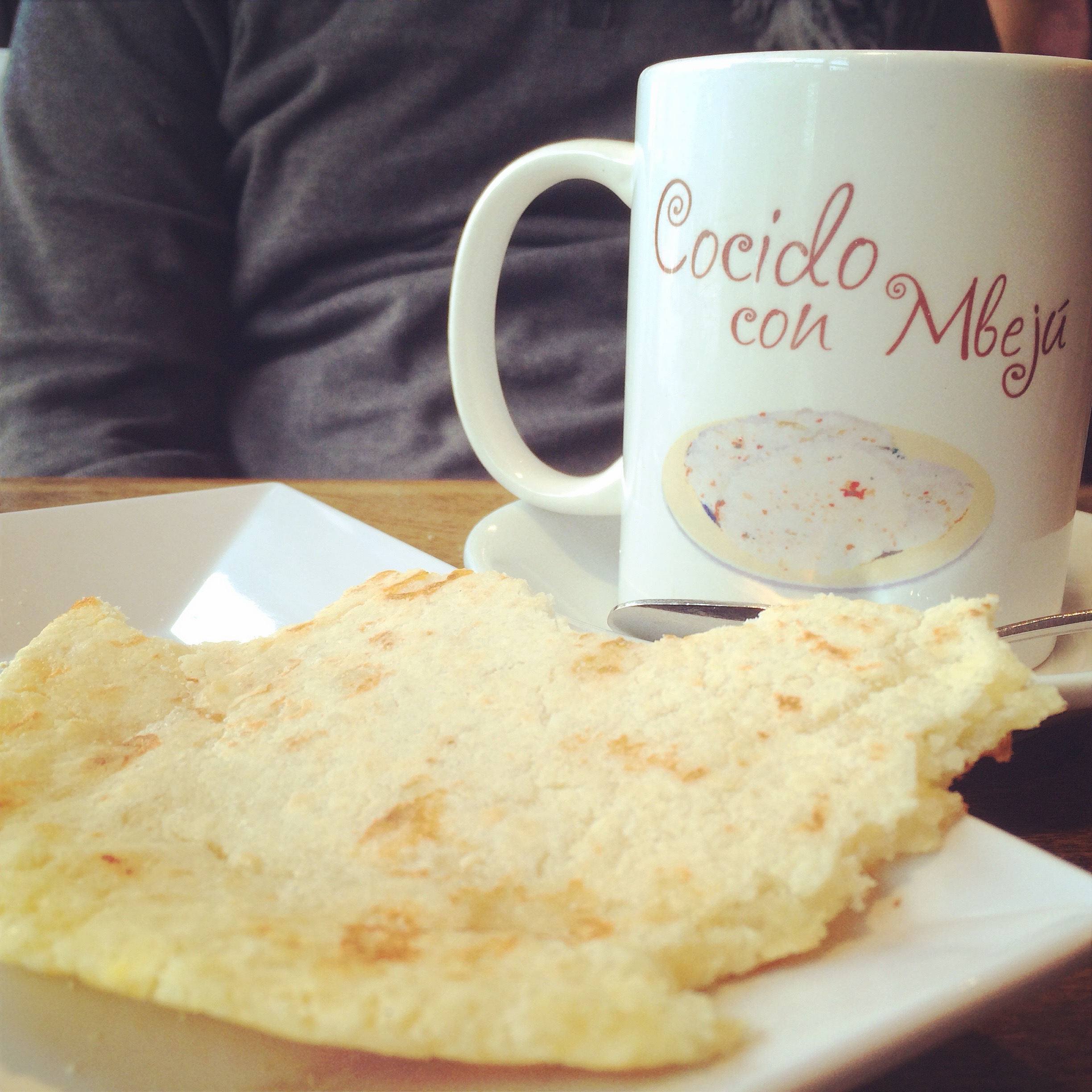 Un mbejú redondo al lado de una taza de cocido