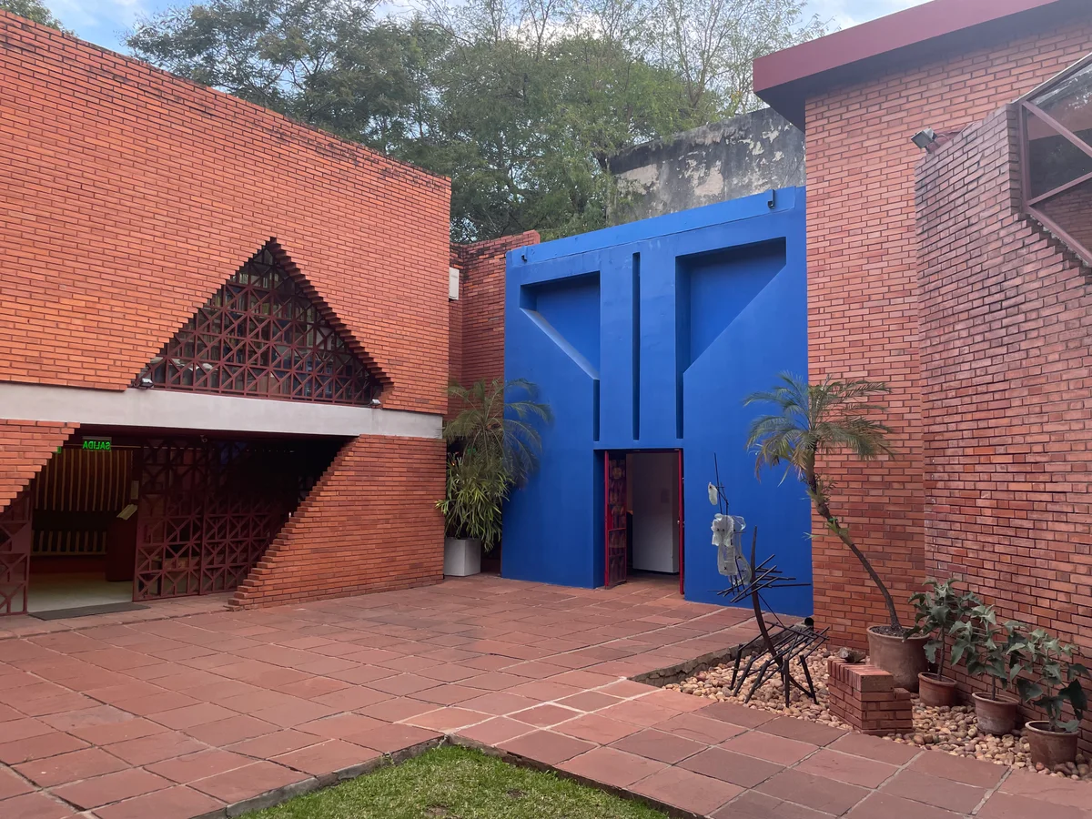 Pátio de tijolos e entrada azul do Museo del Barro em Assunção