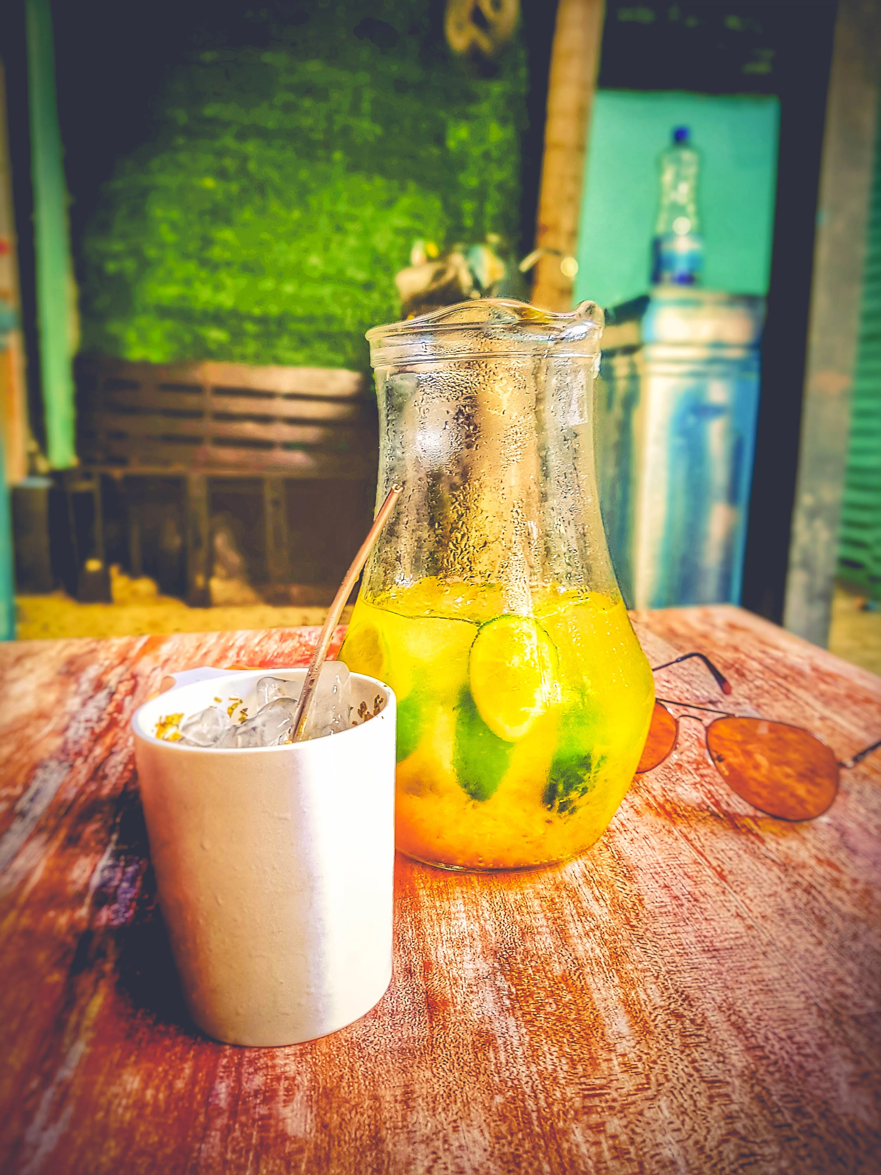 A pitcher of tereré with citrus and a guampa cup on a table